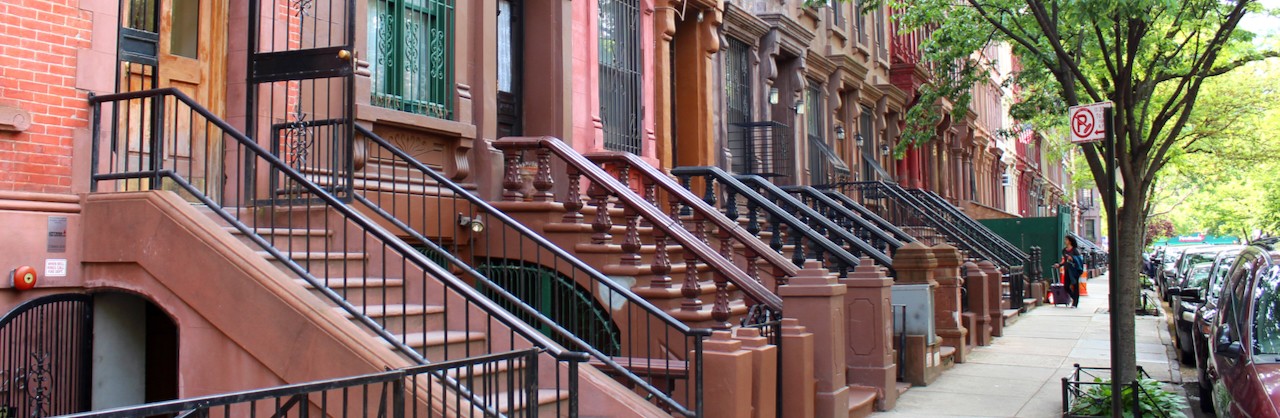 A streetscape of brownstones in Harlem.